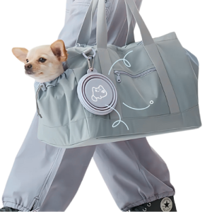 Petit chien dans sac de transport gris, gamelle silicone pliée accrochée sur le côté, avec médaille chien.